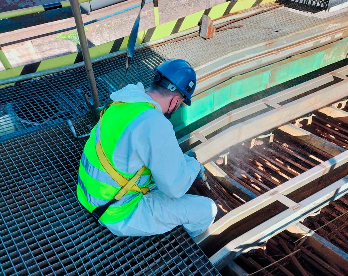 Técnico de INSA des realizando la limpieza de una torre de refrigeración industrial en Galicia con equipo de protección.