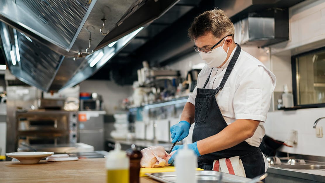 Profesional trabajando en cocina industrial con medidas de higiene y seguridad alimentaria en Galicia